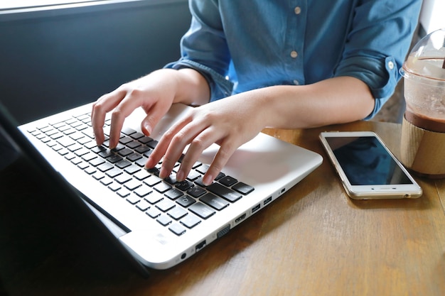 Photo hand multitasking woman working on laptop and phone connecting wifi internet.