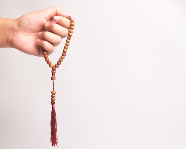 Hand of muslim woman holding a prayer beads isolated on white\
background with copy space.