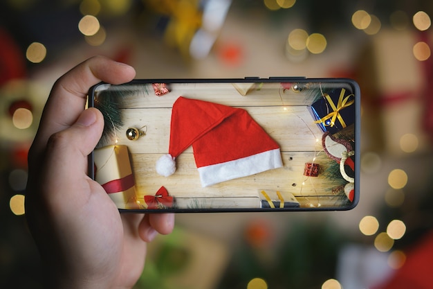 Hand nemen foto van kerstmuts met oneindige display-smartphone