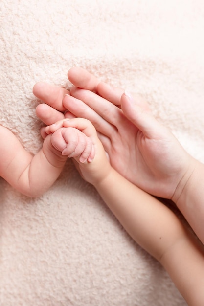 The hand of a newborn in the hand of his older brother and parents family of four