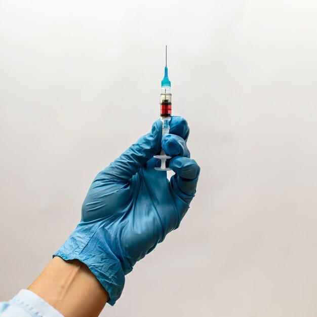 the hand of a nurse in nitrile blue gloves holds a syringe with a medicine selective focus