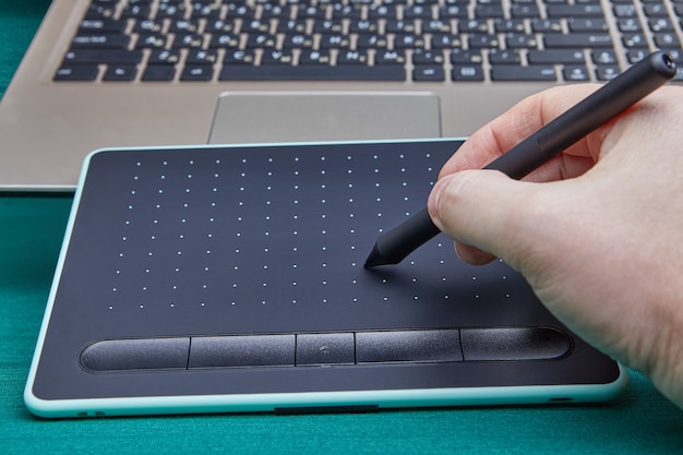 写真 グラフィックエディタプログラムで作業するために電子製図板を使用してスタイラスペンを持つアーティストの手。