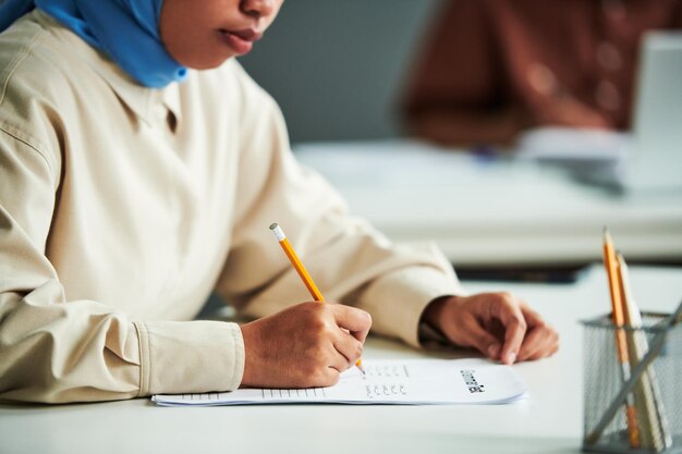 사진 연필로 젊은 이슬람 여성 학생의 손
