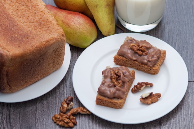 Hand of zelfgemaakte chocoladedeeg met noten. Gezonde snack. Melk, peren, brood.