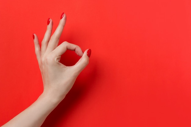 Hand OK sign isolated on red background