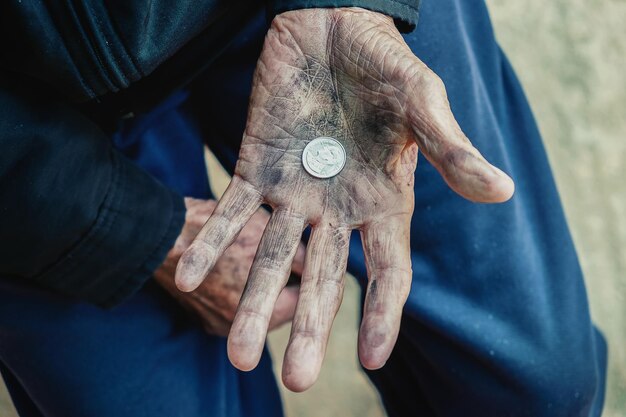 Photo hand old man begging for money because of the hunger on the wood table vintage tone