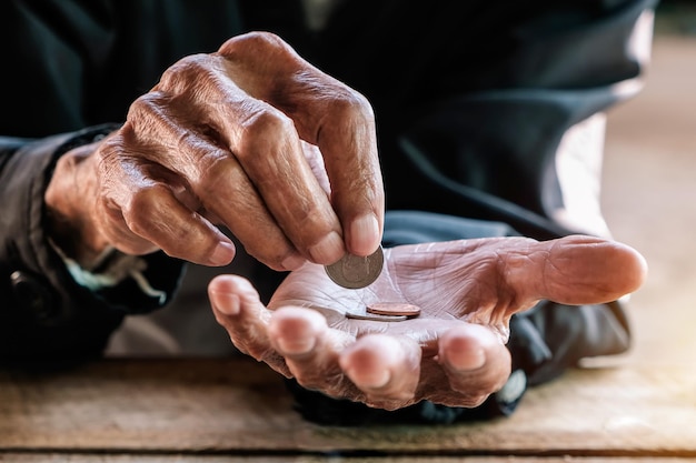 hand old man begging for money because of the hunger on the wood table vintage tone