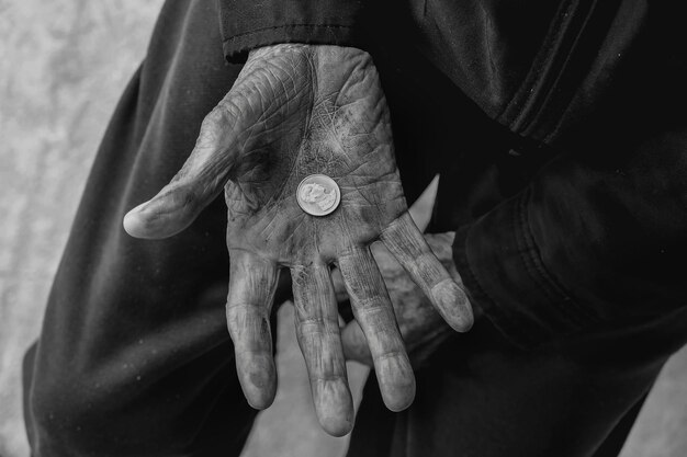 Photo hand old man begging for money because of the hunger on the wood table vintage tone