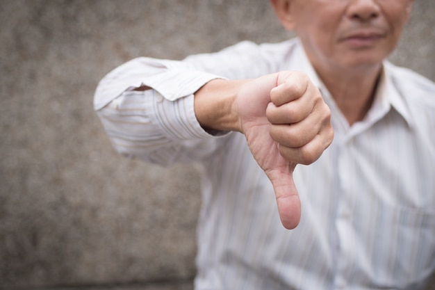 Hand of old senior man giving rejecting thumb down gesture