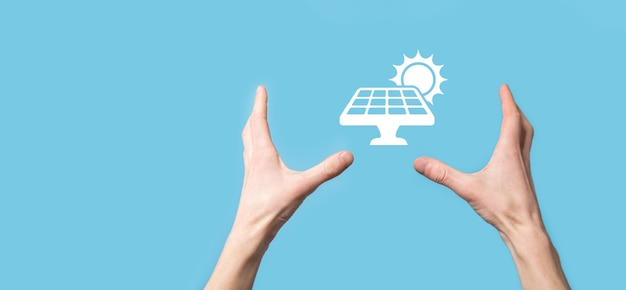사진 파란색 배경에 있는 손에는 태양 전지 패널의 아이콘 기호가 있습니다. 재생 에너지, 태양 전지판 스테이션 개념, 녹색 전기