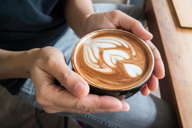 Hand op hete koffie latte