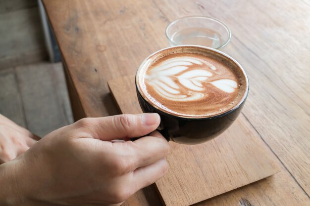 Hand op hete koffie latte