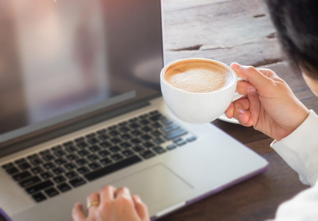 Hand op kopje koffie op de werktafel