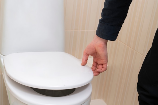 A hand open the toilet lid, home household sanitary