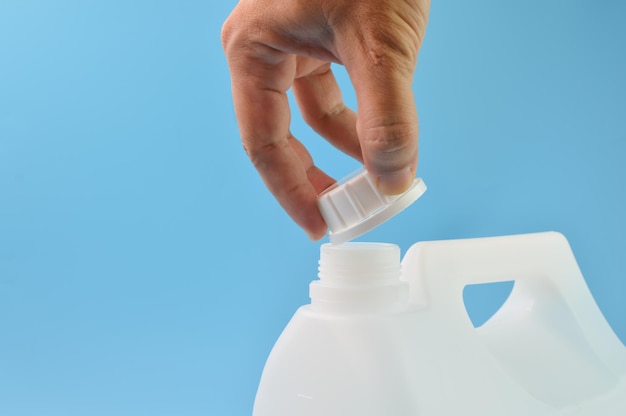 Hand opened white gallon bottle cap isolated on a blue background