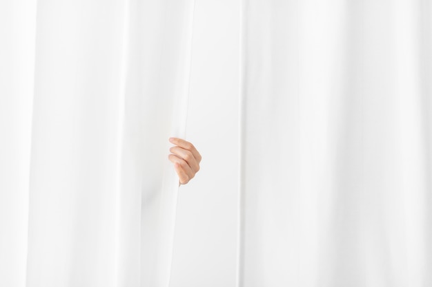 Photo hand opening a white curtain