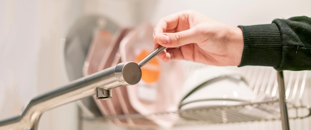 Hand opens the kitchen wateraucet tap close up