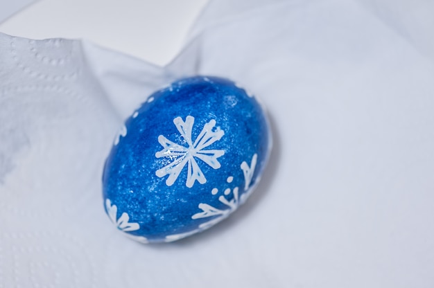 Hand painted blue easter egg on white paper napkin.