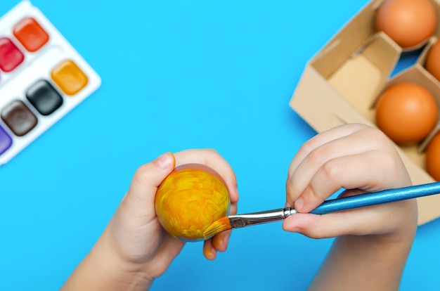 Hand-painted Easter eggs before Easter. Preparing for Easter, on a blue background. Multicolored paint, copy space.