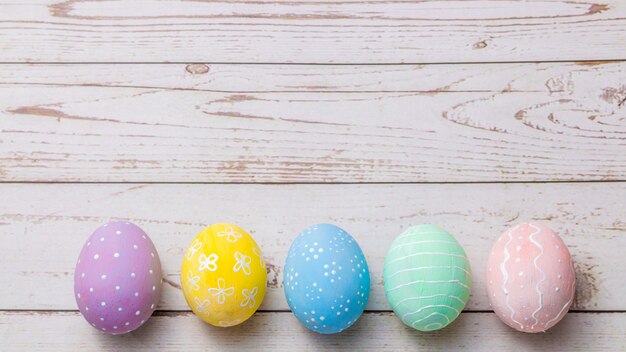 Hand painted pastel colors eggs on light colored wooden table.