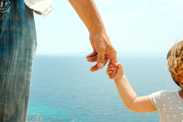 Hand of parent and child near the sea