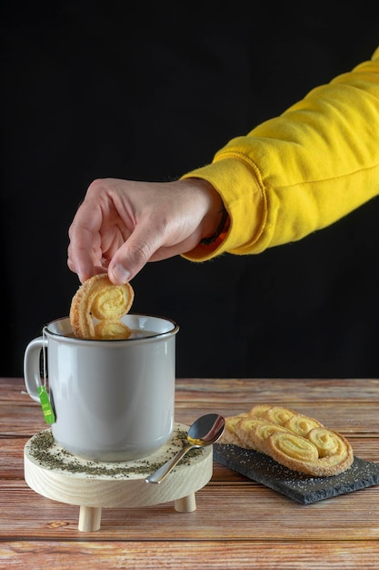 Hand of a person dipping a cookie into a cup of hot tea ready to eat