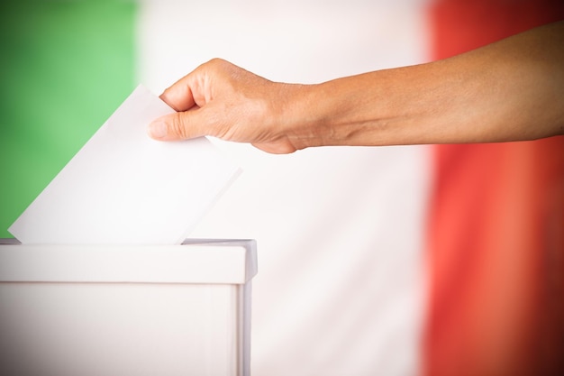 Hand person putting ballot in a box during elections in italy