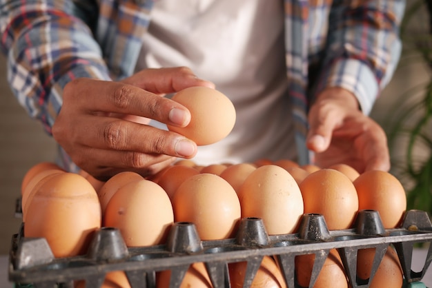 Hand pick eggs from a plastic case on table