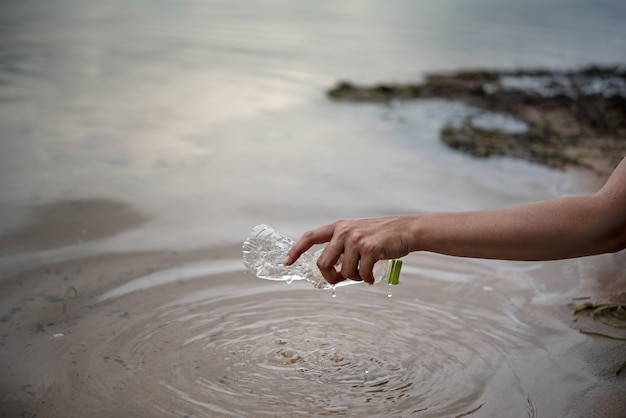 Рука забрать пластиковую бутылку из воды