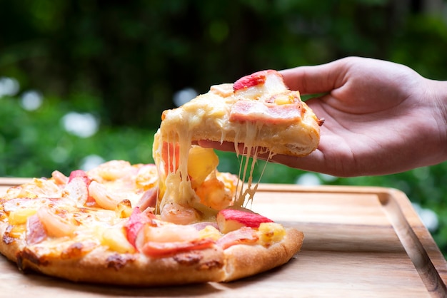 Foto pizza ai peperoni raccolta a mano sul tagliere di legno