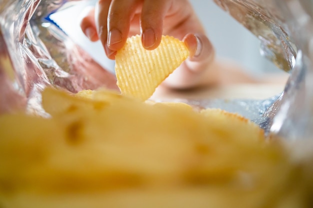 Hand picking potato chips inside snack bag