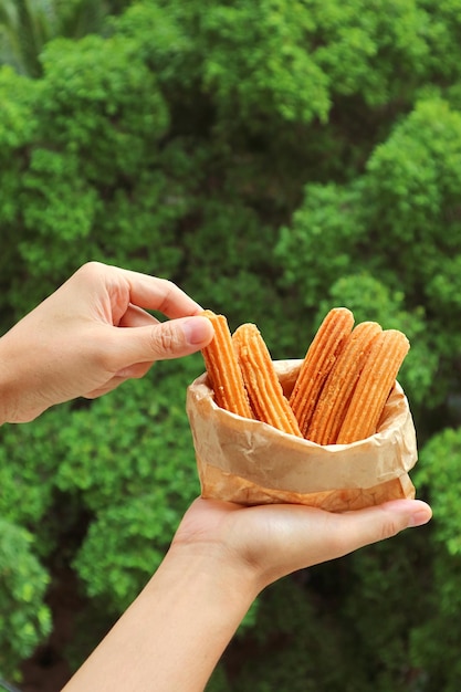 Raccogliendo a mano un bastoncino di churro appetitoso dal sacchetto di carta