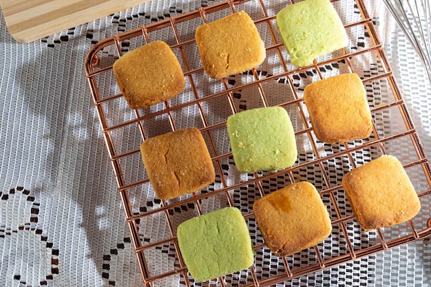 hand picking up homemade cookie on pink wire cooling rack