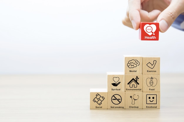 Hand picking up medical and health symbol on a wooden toy block.