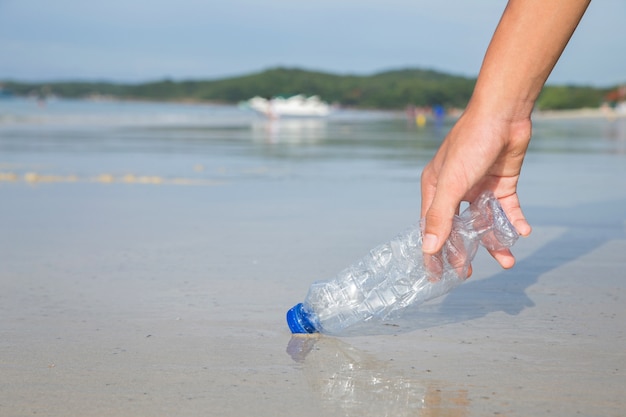 Raccogliendo a mano la pulizia delle bottiglie di plastica sulla spiaggia.