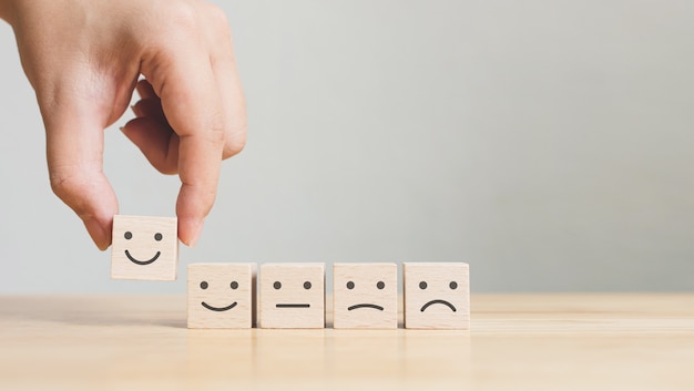 Hand picking up wooden cubes with simley and sad faces on them