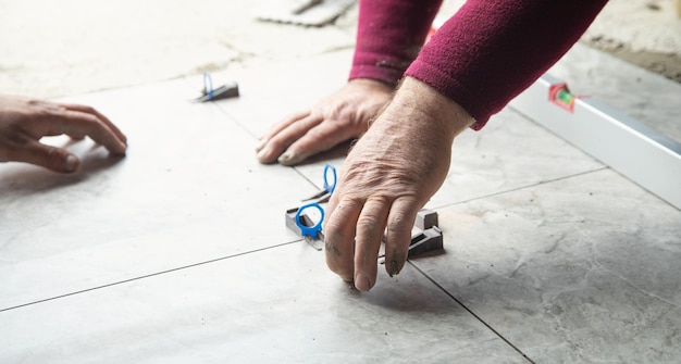 Hand plaatst een plastic clip tussen de tegel