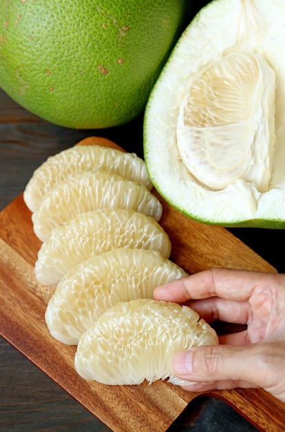 Hand Placing Fresh Pomelo Fruit Segments after Peeled on a Cutting Board