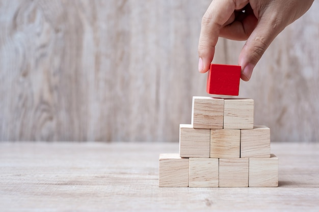 Hand placing red wooden block on top