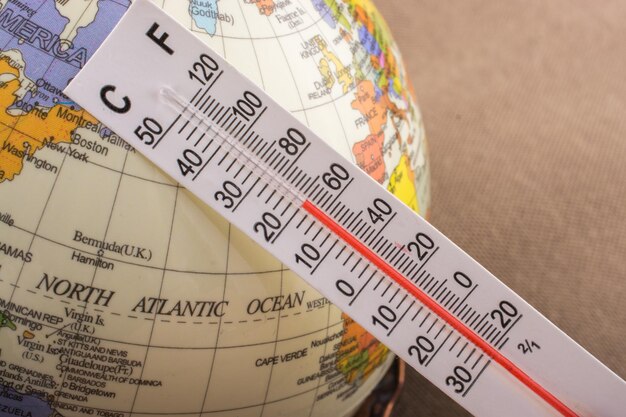 Hand placing a thermometer on a model globe