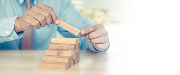 Hand placing wood block tower stack in pyramid stair step