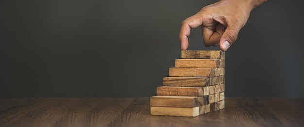 Hand placing wood block tower stack in pyramid stair step