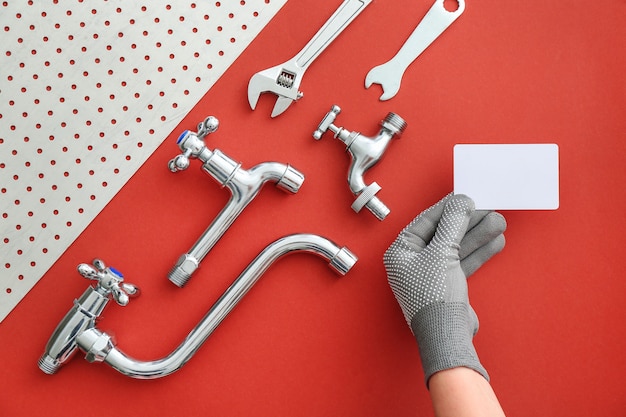 Hand of plumber with business card and items
