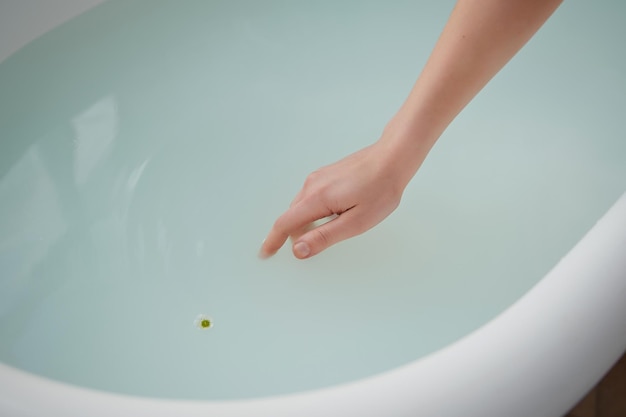 the hand plunges into the water tub filled with milk swims a little flower