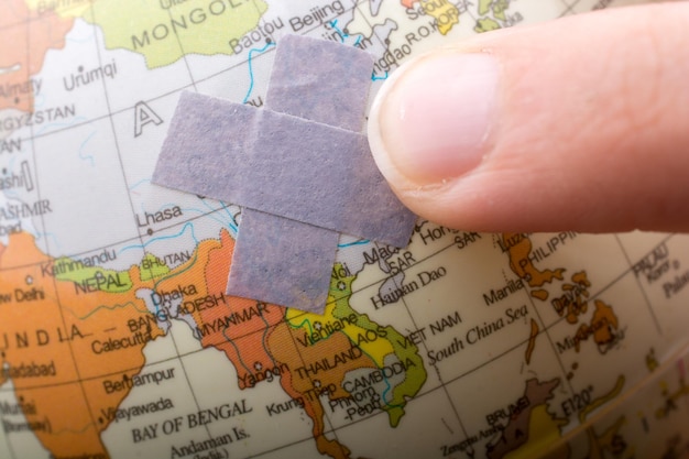 Photo hand pointing to a bandaid on the globe on display