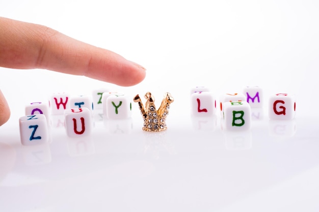 Photo hand pointing at crown between letter cubes on a white background