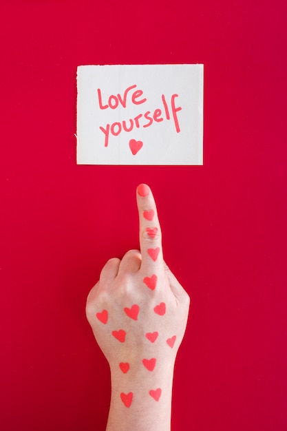 Hand pointing finger at Love yourself message 