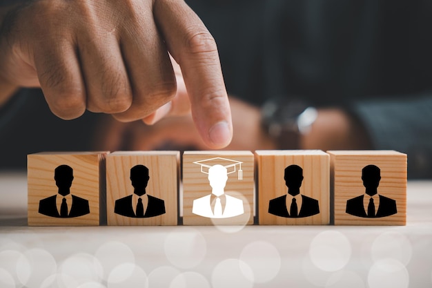 Hand points to a red human icon on a wooden block Business hiring and recruitment selection in Human Resource Management Leadership and teamwork for success in competitive market Human resources