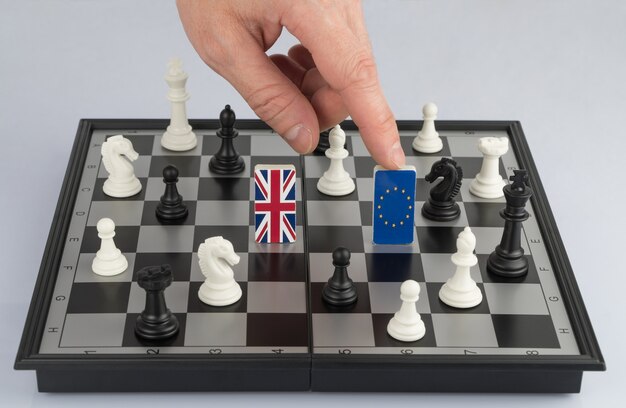 Рука политика поднимает фигуру с флагом Европейского Союза Политическая игра и стратегия