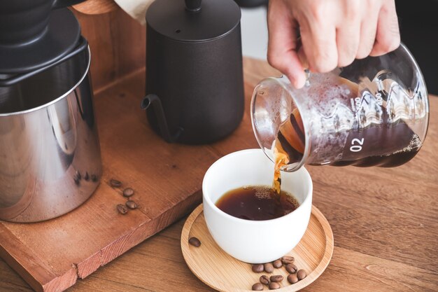 A hand pouring drip coffee into a mug